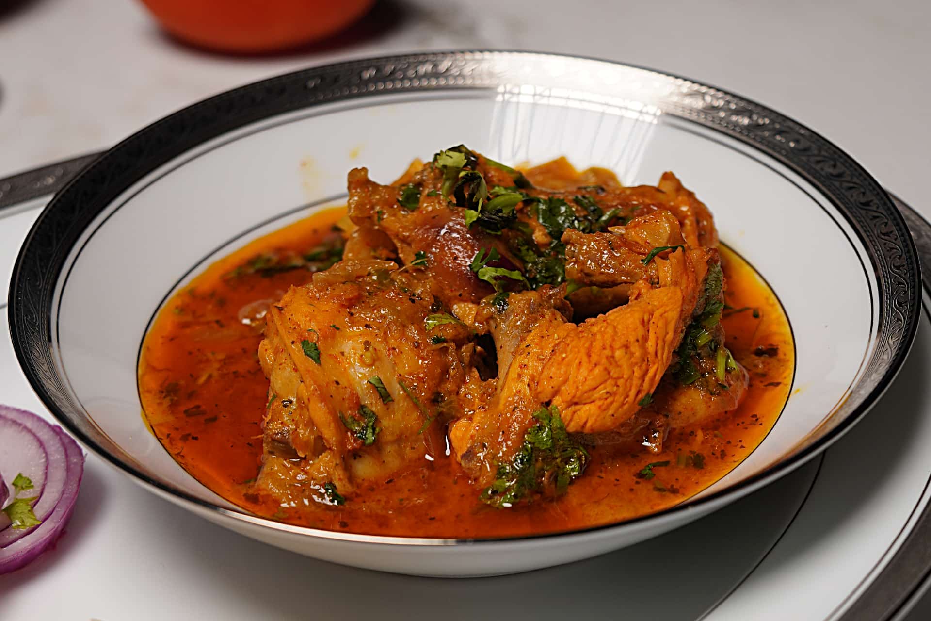Traditional Surati Chicken Tapelu served in bowl, garnished with fresh herbs