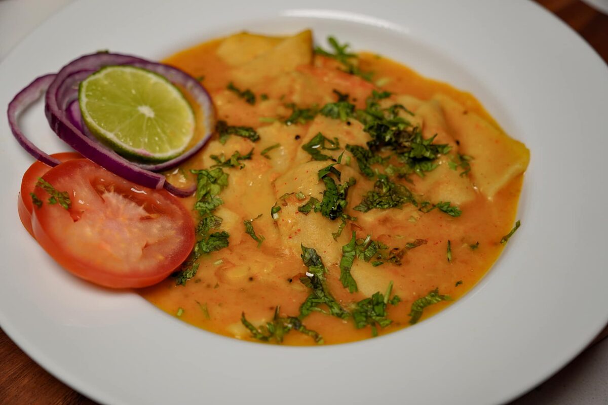 A serving plate filled with steaming hot Dal Dhokli, garnished with fresh coriander and a drizzle of ghee.