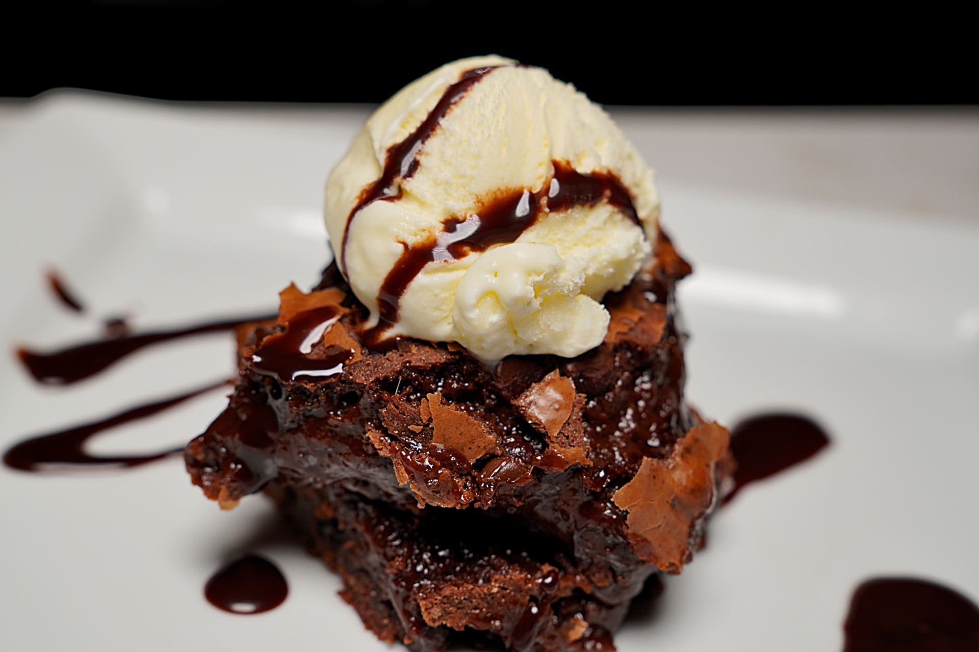 Fudgy brownies topped with a scoop of vanilla ice cream, creating a delightful dessert.