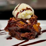 Fudgy chocolate brownies layered and topped with a scoop of vanilla ice cream.