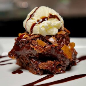 Fudgy chocolate brownies layered and topped with a scoop of vanilla ice cream.