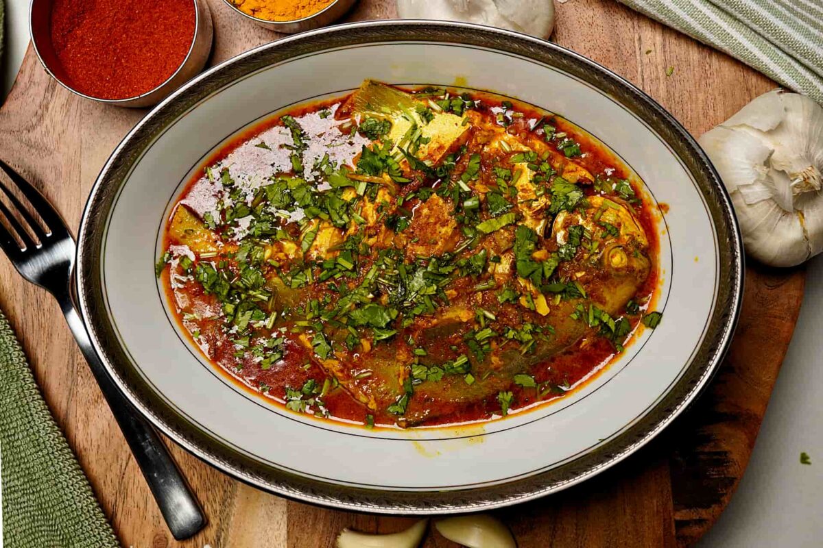 Pomfret Fish Curry garnished with fresh coriander leaves and green garlic.