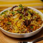 Overhead view of Dal Biryani highlighting colorful rice, herbs, and crispy fried onions
