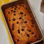 Whole loaf of freshly baked eggless banana bread topped with semi-sweet chocolate chips