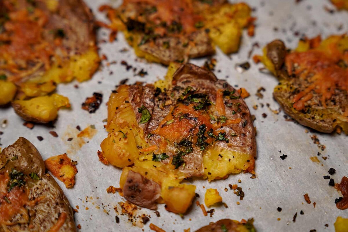 Close-up of smashed potatoes showing crispy edges and herb garnish