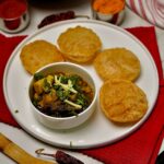 Overhead view of golden crispy puris with aromatic potato curry garnished with fresh coriander
