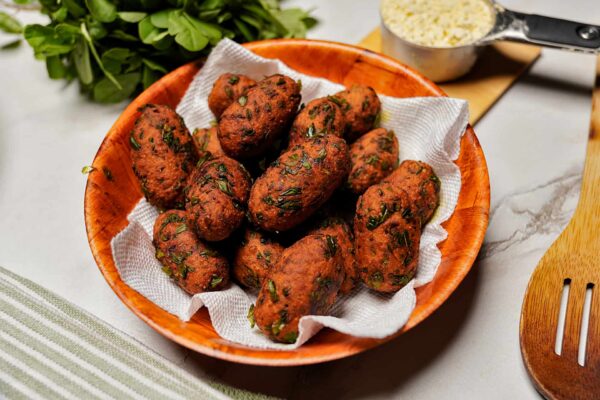 Overhead view of Methi Na Muthia arranged in basket, highlighting their oval shape and texture.