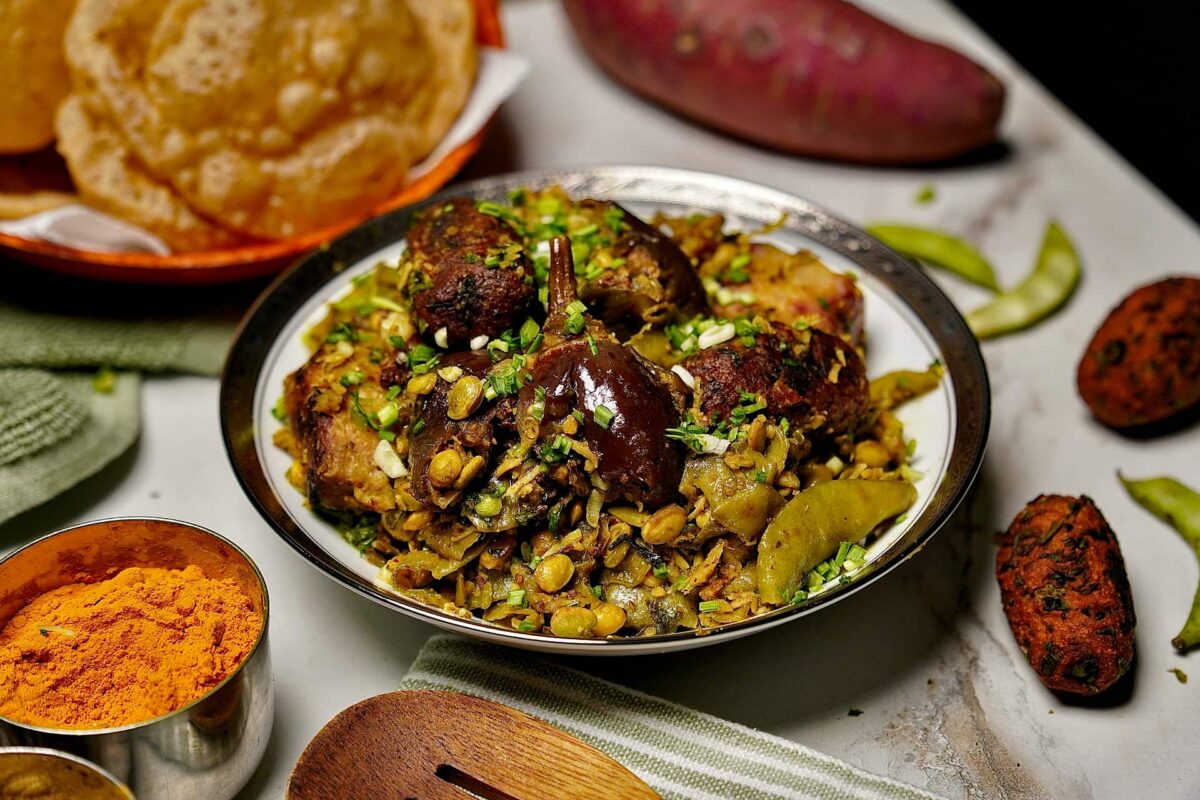 Traditional Surti Undhiyu served in a pot with colorful mixed vegetables and crispy methi muthia