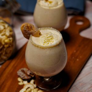 Kaju Anjeer Milkshake topped with a scoop of vanilla ice cream, served in a glass.