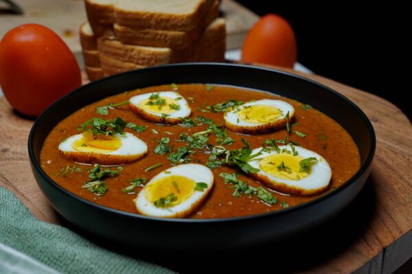 Beautifully plated spicy egg curry ready to be served, highlighting the vibrant gravy and breads on side.