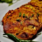 Close-up of garnished Ringan Na Palita with chopped green garlic and coriander leaves on top.