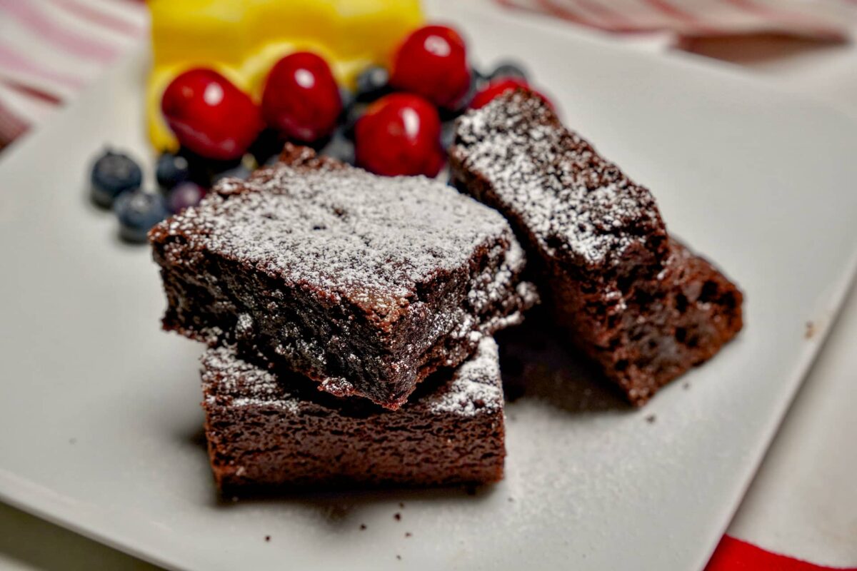 Freshly cut eggless brownies revealing a rich, fudgy chocolate interior with crackly top
