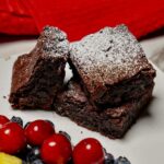 Eggless brownies arranged on a plate platter with berries