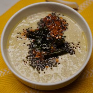 A bowl of traditional white coconut chutney served with fresh coconut slices in the background, highlighting the authentic ingredients used in the recipe.
