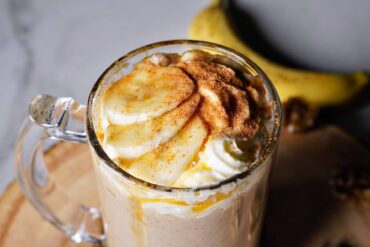 Creamy Peanut Butter Banana Smoothie garnished with banana slice and drizzle of maple syrup and cinnamon
