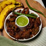 Overhead view of Kela Methi Na Bhajiya, showcasing the golden fritters with fresh methi leaves and ripe bananas.