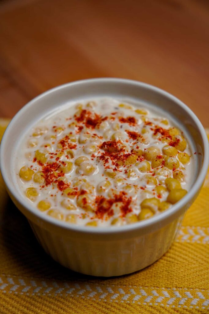 A top-down view of a bowl of Boondi Raita, showcasing the vibrant green garnish and perfectly distributed boondi pearls.