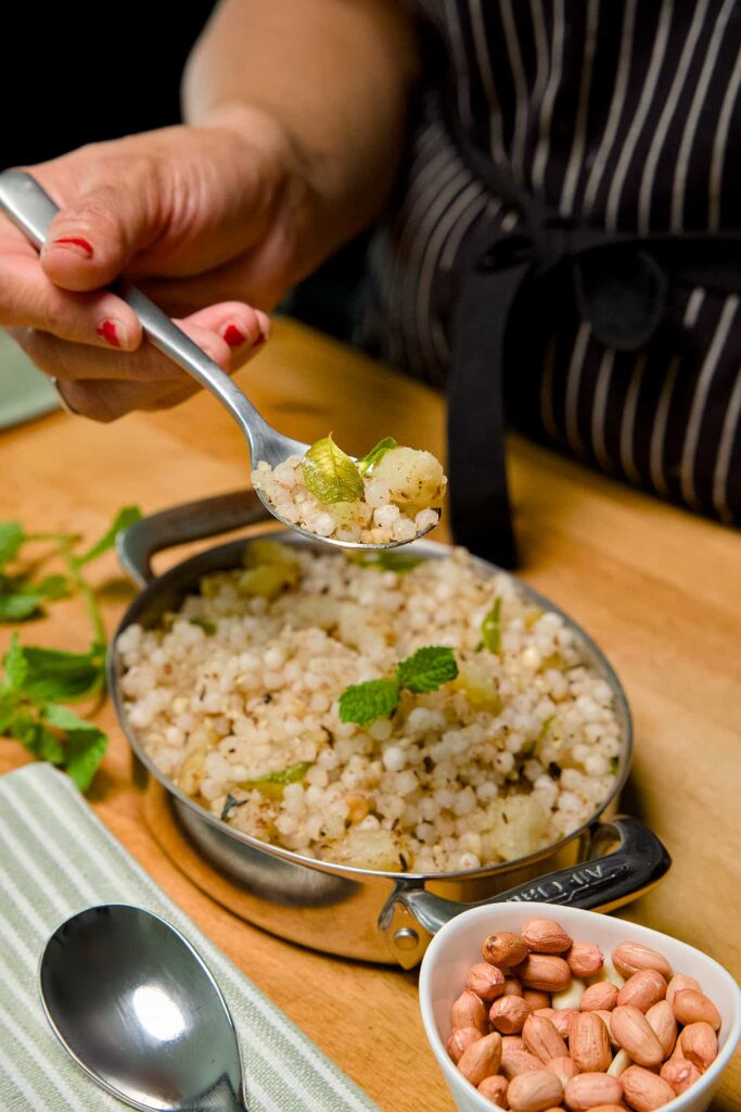 An eye-level side view of Sabudana Khichdi in a bowl on a rustic wooden board, showing the soft texture of the tapioca pearls.