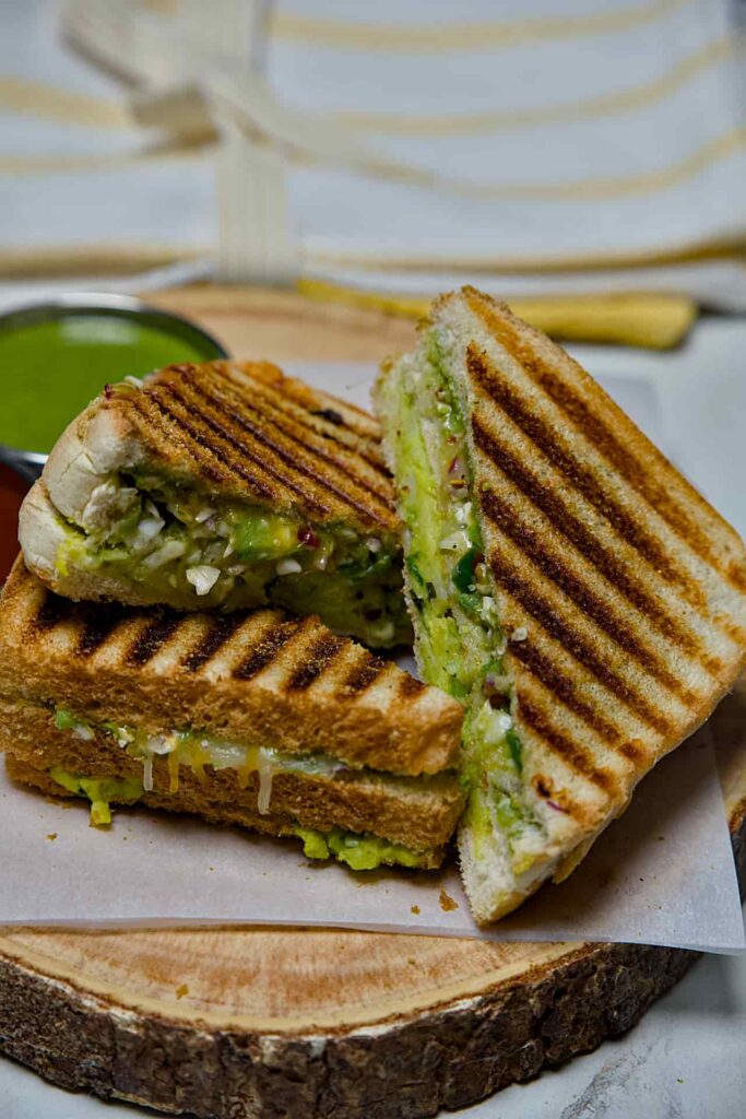 Two halves of a crispy Bombay Grill Sandwich stacked vertically to show the generous vegetable and potato stuffing inside.