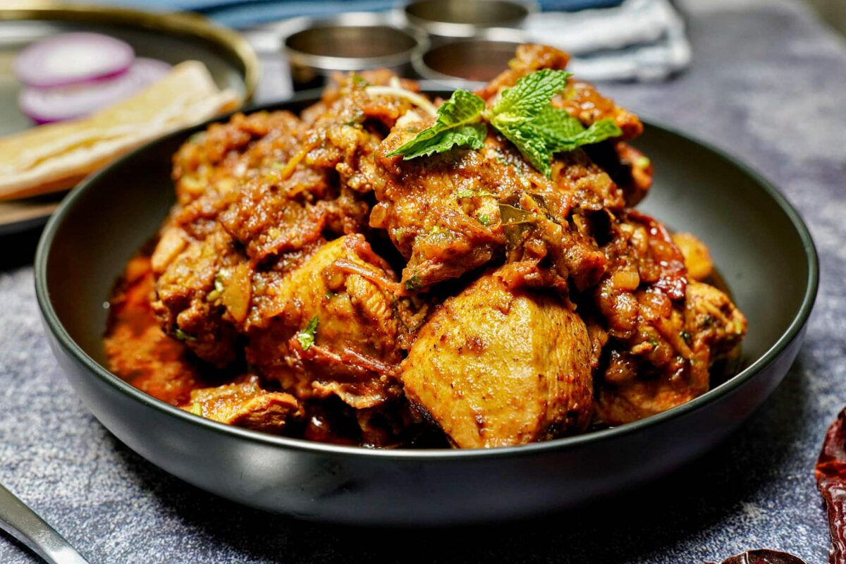 A plate of Chicken Chettinad served with onions and roti ready to enjoy.