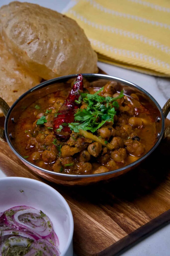 Rich chickpea curry topped with sizzling ghee tadka, julienned ginger, cilantro, and whole kashmiri red chili.